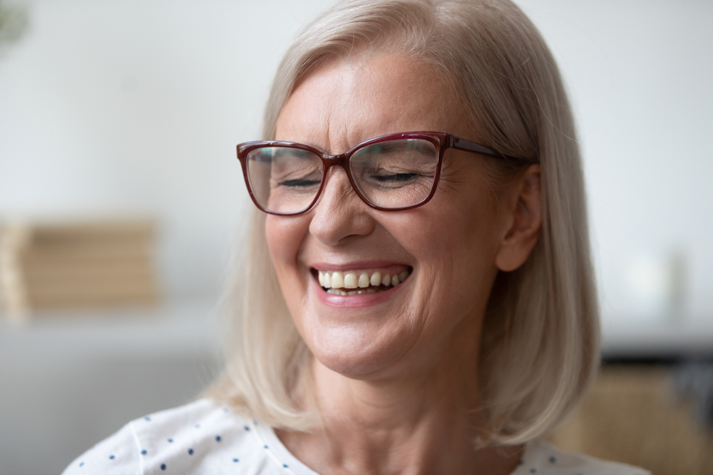 Dental Implants in the San Diego Community: Smiling at Any Age Mature woman wearing glasses and laughing, reflecting the full range of patients who benefit from dental implants in the San Diego community