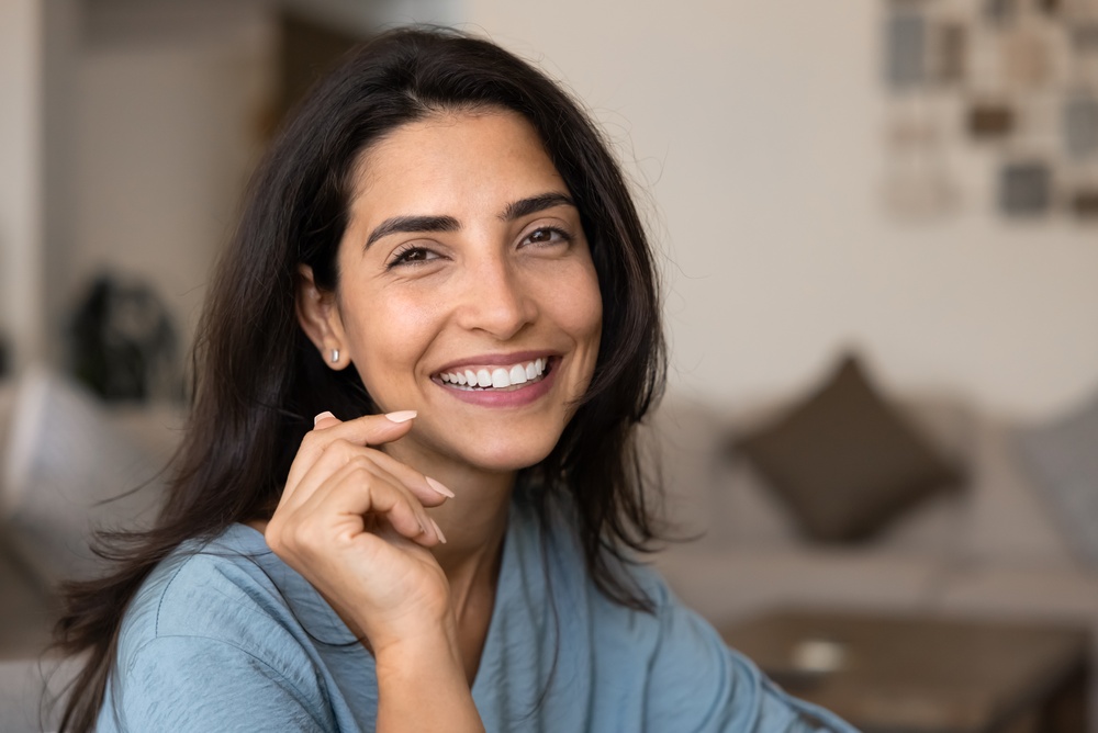 Dental Implants Del Mar: Confident Smile at Home Smiling woman resting her chin on her hand at home, representing the confident smile dental implants for Del Mar patients can help achieve