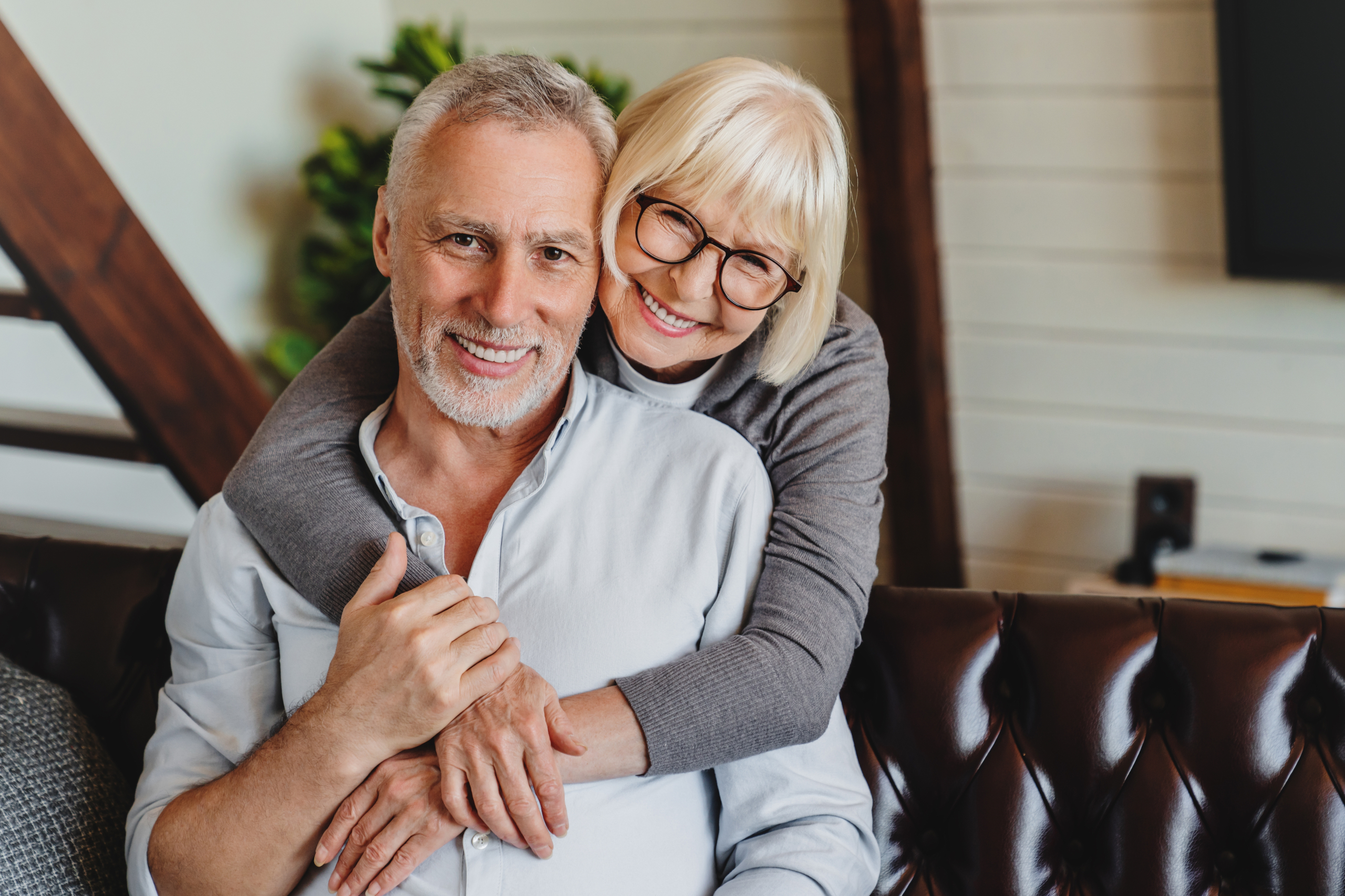 Smiling mature couple embracing at home, reflecting confident smiles from general and cosmetic dentistry in the San Diego community 