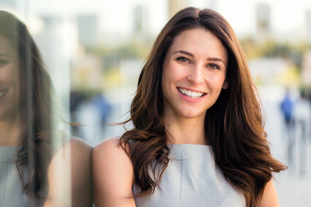 Woman smiling outdoors with a bright, white smile, highlighting cosmetic dentistry and teeth whitening results in the San Diego community 